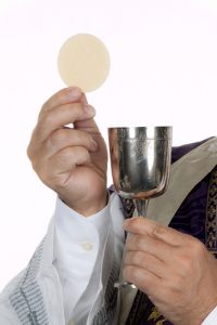 a catholic priest with a chalice and paten at holy communion