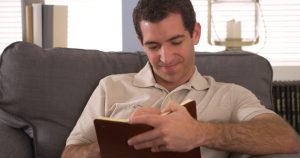Man writing down notes in book