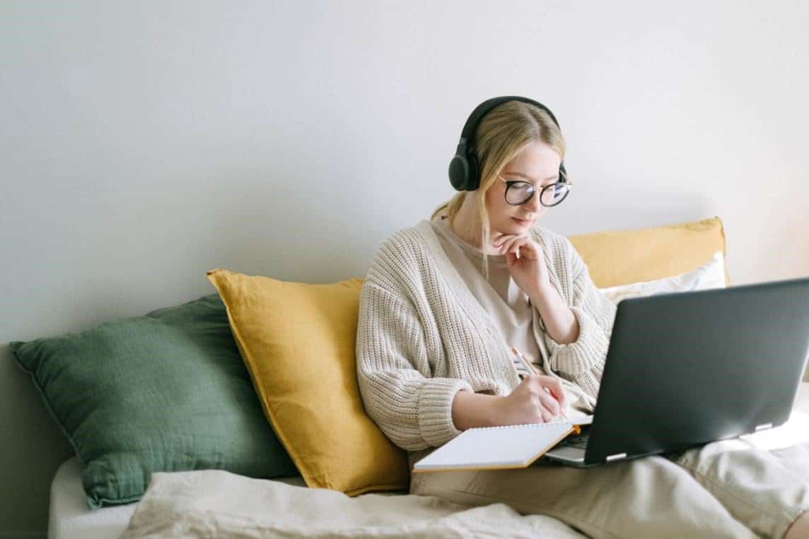 A woman writing something on the laptop and in a notebook—a way to turn your hobby into a business