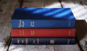 Must-read books for Christians stacked upon one another, including works of Emily Bronte, Charles Dickens, and Jane Austen